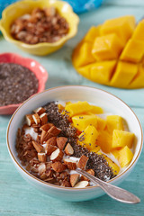 mango and greek yoghurt with seeds and nuts on wooden surface