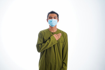 An Asian young man isolated on white background with casual entire and wearing a face mask. Hand gesture stop, sick, respect. during corona virus 