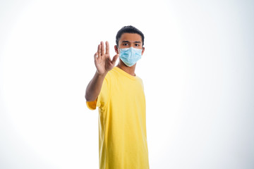 Fototapeta na wymiar An Asian young man isolated on white background with casual entire and wearing a face mask. Hand gesture stop, sick, respect. during corona virus 