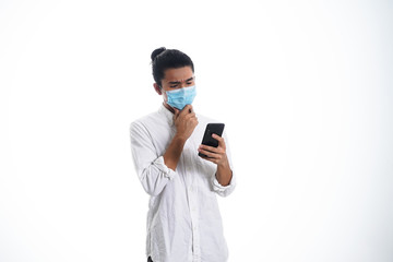 An Asian young man isolated on white background with casual entire and wearing a face mask. Hand gesture stop, sick, respect. during corona virus 