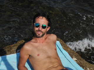 Hombre tumbado en la toalla enfrente del mar