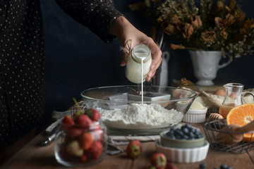 Pouring milk on flour for bake baking, Concept of cooking ingredients and method. Dessert recipes and homemade.