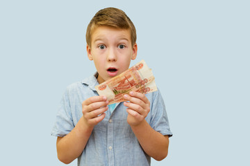 a schoolboy a boy of 10 years of Asian appearance holding in his hands banknotes of 5 thousand Russian rubles on an isolated background finance theme