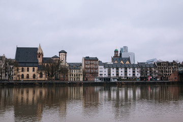 Skyline of Old city of Frankfurt at dusk from opposite side of river in fog rainy day.