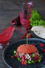 Fashion pink burger with chicken and raspberry homemade vinaigrette. Inside chicken breast, red onion, lettuce, cucumber and raspberry home-made vinaigrette. An unusual combination. Diet burger.