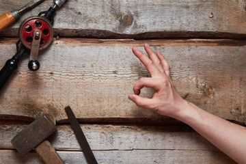 Hand holds old carpentry tools on wooden background.