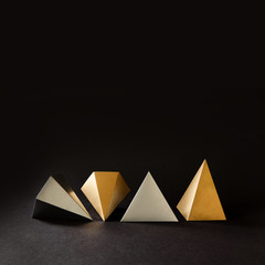 Minimal geometry still life composition. Platonic solids figures geometry. Abstract gold and silver color geometrical figures. Three-dimensional pyramid objects on black background