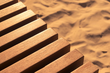 part of a wooden bench against a background of sand