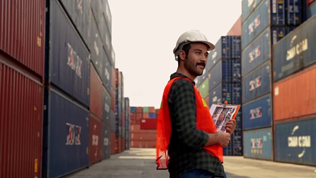 Engineers wear safety-helmet while working in the container transportation industry, inspecting warehouse work.
