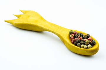 Wooden spoon with a mixture of peppers isolated on a white background.