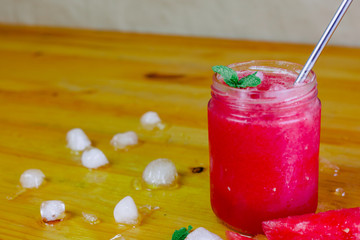 Close-up of a watermelon slush with an aluminum straw and watermelon triangles with ice and peppermint