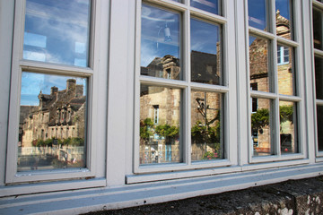 reflection of stone houses in a window in locronan (brittany - france)