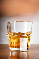 Whiskey with ice in a glass glass on a wooden table in a bar