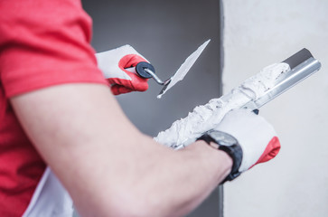 Construction Worker Applying Drywall Compound On Taping Knife.