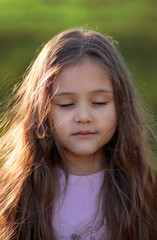 portrait of a little girl with long hair on summer nature