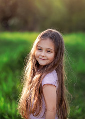 portrait of a little girl with long hair on summer nature