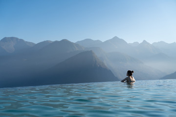 Sexy woman relaxing in infinity swimming pool   looking at stunning mountain view at  luxurious...