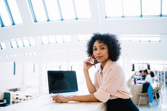 Portrait of attractive black female entrepreneur calling to customer service for consultancy about account balance on smartphone gadget, afro american manager near desktop using 4g for talking