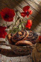 Still life with muffins with poppy and red poppies on a old wooden background. Vertical orientation.