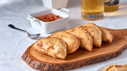 Empanadas argentinas traditional food on wooden ray with sauce and beer