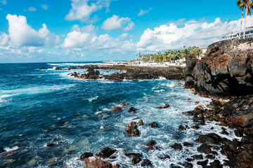 The coast of the island of Tenerife. Tourist season on a tropical island. Volcanic beaches and black sand in Spain. Rocks and rocks in the Atlantic ocean. Trekking and excursions in the Canary Islands