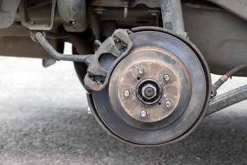 Rusty back car wheel hub with brake disc at tire shop. Car without a wheel while replacing on the tire service center. Closeup view