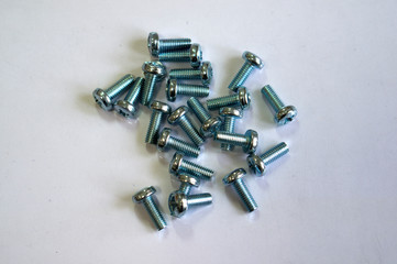 A large number of bolts on a white table. Fixing bolts. New bolts.