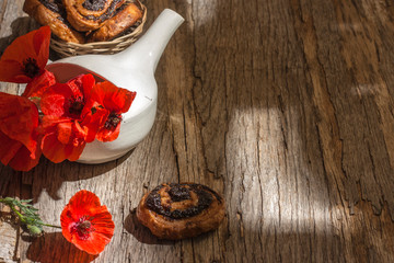 Still life with red poppies in a white bowl on a wooden old background with poppy muffins with copy space.