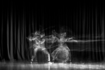 An artistic dancer in a theater shot with a slow shutter speed in order to achieve the desired motion blur.