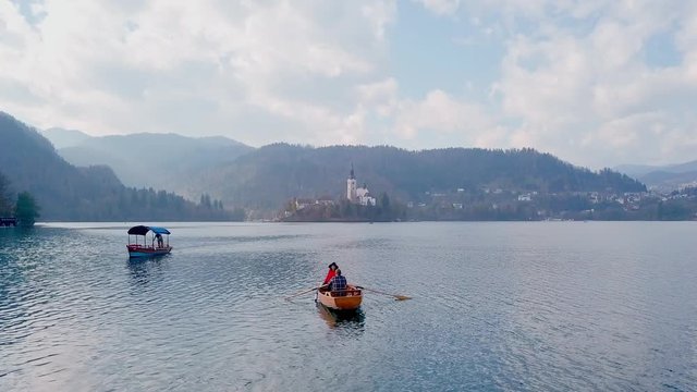 Young couple kayaking together and enjoying magnificent view of the Alph mountains during honeymoon. Bird's-eye or drone view. Smiling guy paddling and talking to his girl. Copter shot couple in boat.