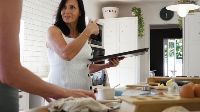 Mother and daughter baking scones together and placing tray in the oven