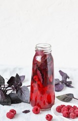 homemade raspberry vinegar with purple basil and garlic. In a bottle on a light background. copy space