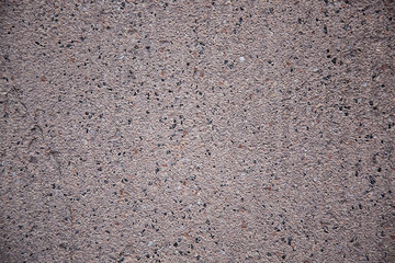 Grey-brown background of porous stone, rough surface of the material, details on the stone wall