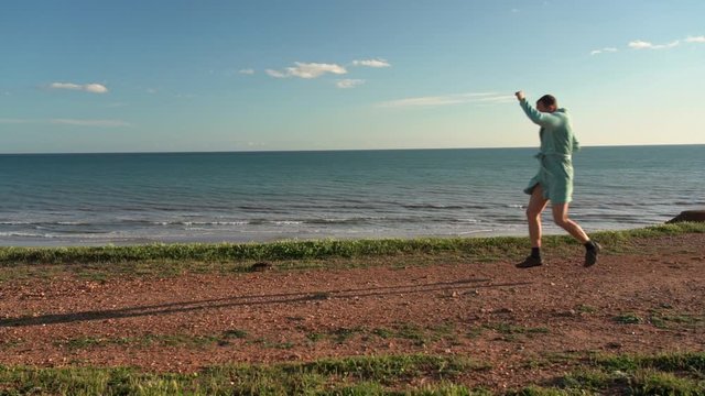 A middle-aged man in a housecoat, on the ocean, jumps, seized with happiness from winning the lottery. Slow motion.