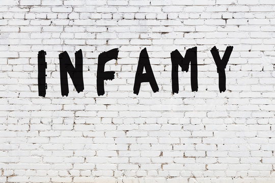 Word infamy painted on white brick wall