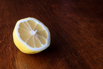One half of a ripe, juicy lemon on a brown tabletop