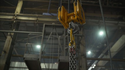 Low angle view of manual worker operating crane lifting sheet metal in industry. Crane in the...