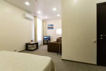Interior of a beautiful hotel bedroom is decorated in brown and white tones.
