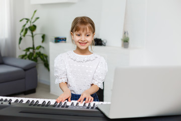 Home lesson on music for the girl on the piano. The idea of activities for the child at home during quarantine. Music concept