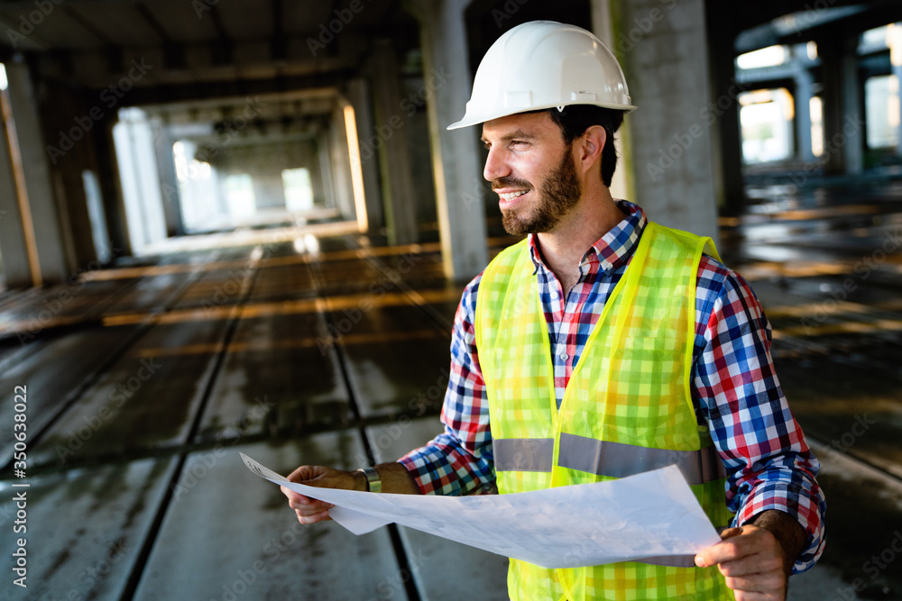 Wall mural architect, engineer looking at blueprints in a construction site