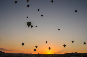 The sunrise in the mountains with Hot air balloons flying over Cappadocia red valley in the sky. Travel to Goreme, Turkey