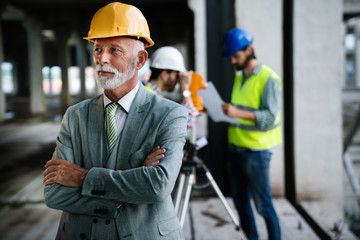 Two satisfied engineers talking at building site with construction structure in background