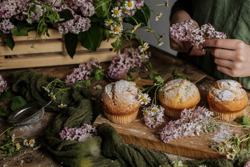 On the table among the lilac branches are vanilla cupcakes