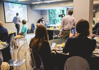 Businessmen, businesswoman and workers from back seated, recording and listen a seminar with...