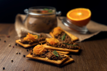 A few crackers with poultry liver pate and orange jam, sliced orange fruits on the sackcloth and...