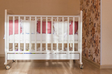 Obraz na płótnie Canvas Baby bed crib with white and Burgundy color pillows with laces