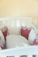 Baby bed crib with white and Burgundy color pillows with laces