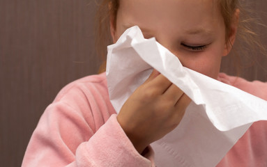 sick girl child sneezes in a napkin