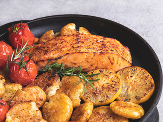 grilled baked salmon fillet with roasted new potatoes , lemon, tomato