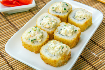 Tempura Maki Sushi-Deep Fried Roll made of Crab Meat, with cucumber. Served on Wooden Plate. sushi Japanese cuisine menu